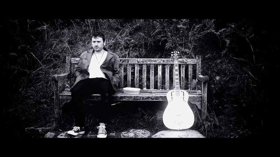 James Fisher as Jonah on a bench with his guitar, Grasmere Lake District, October 2011 - Black Smoke Rising